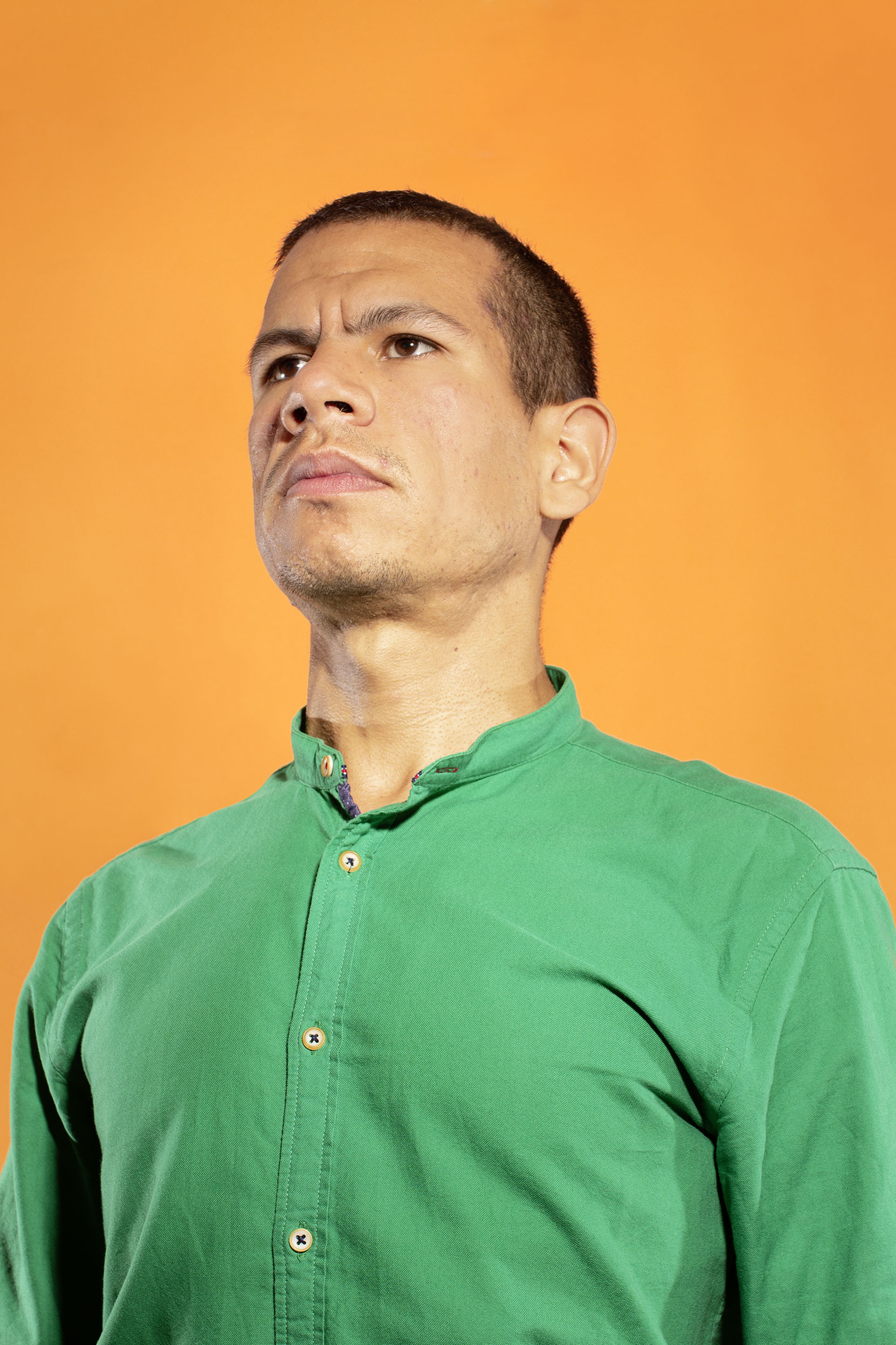 Foto Studioaufnahme Portrait Mann mit grünem Hemd vor orangem Hintergrund autoritäre Pose grimmiger Blick demokratische Schrift Demokratie Oxlos FH Münster Pumpenhaus Festival der Demokratie DemoX8